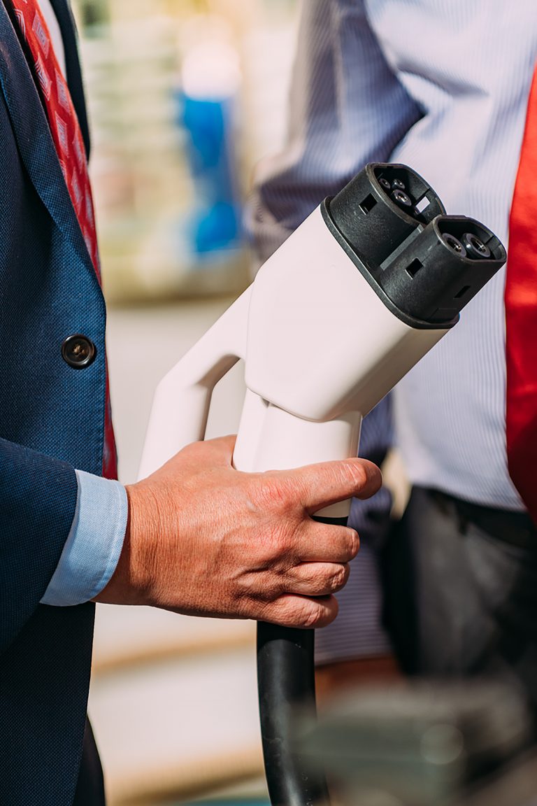 Man wearing a suit holding an electric vehicle charger.