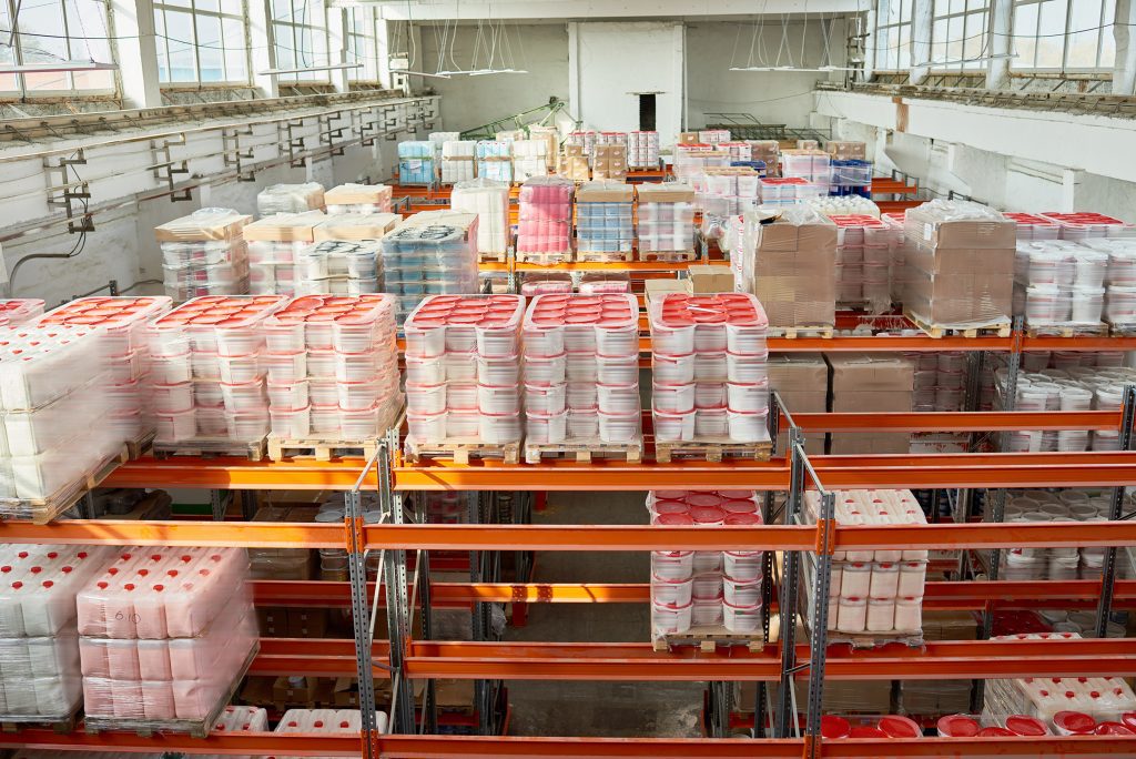 Interior of a warehouse full of tall orange storage shelves packed with goods.